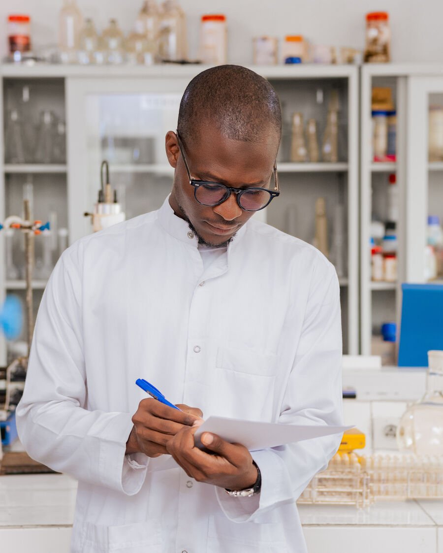 Fawase ADEGBINDIN en laboratoire, prenant des notes