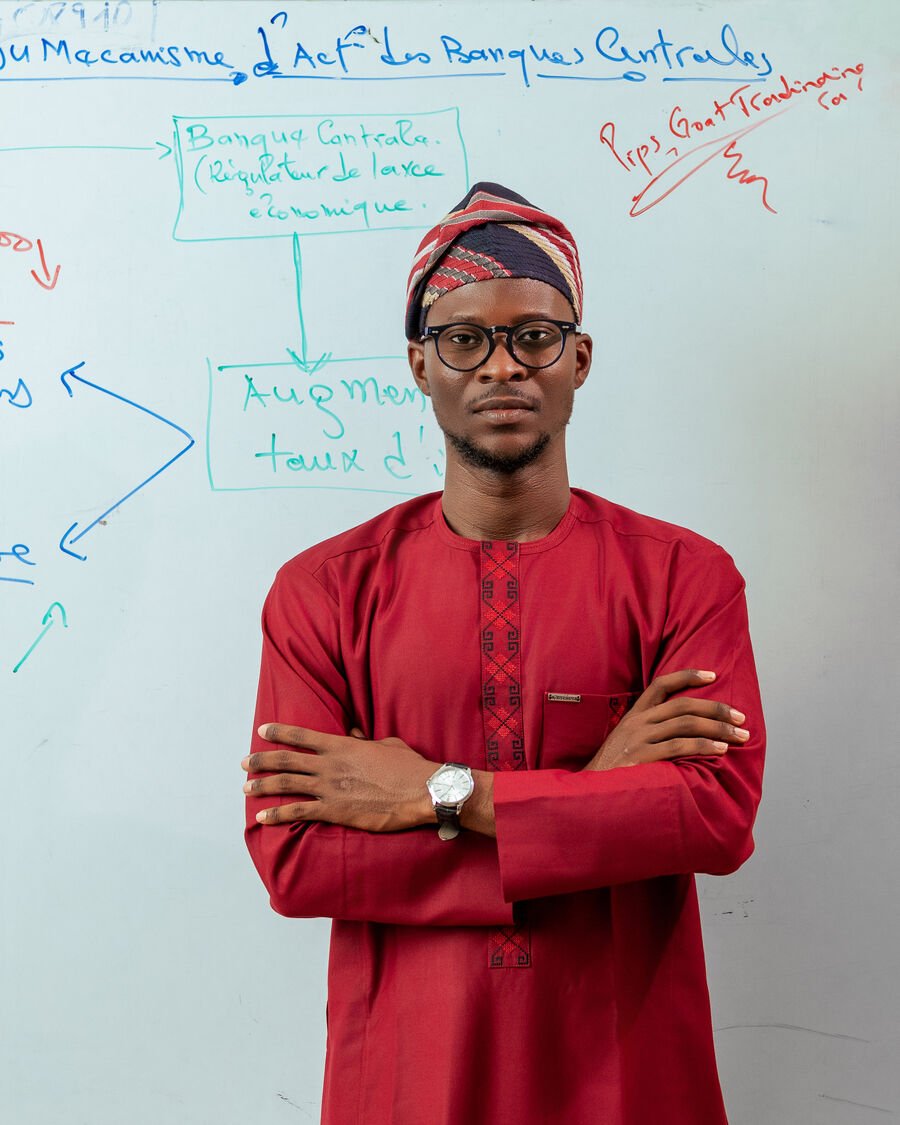 Fawase ADEGBINDIN face caméra devant un tableau de formation Pips Goat