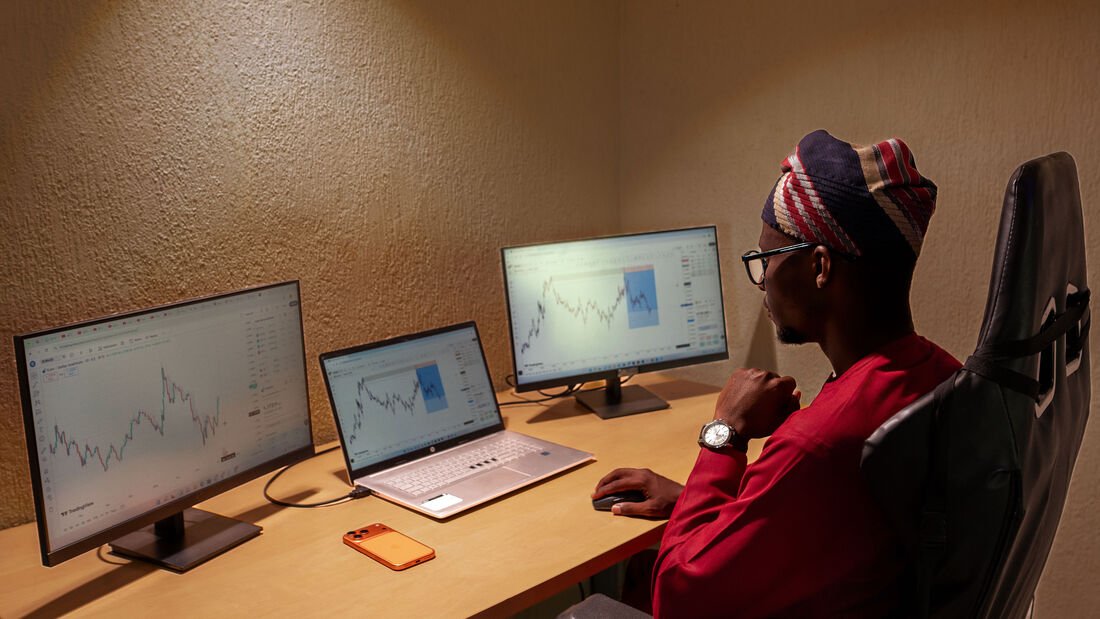 Fawase ADEGBINDIN à son poste de travail multi-écrans, en analyse de marché